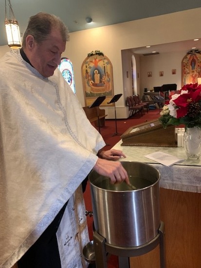Fr. Sergei blessing the water with the silver cross.